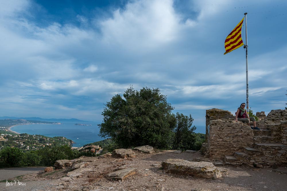 Die Liebste sitzt auf den Mauern der Burgruine, hinter ihr weht die Spanische Flagge.